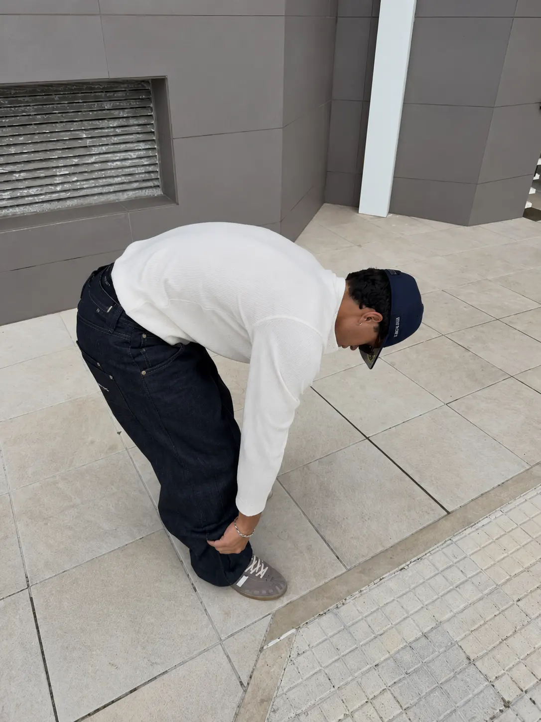 Model wearing the white Matteo Henley adjusting his trousers